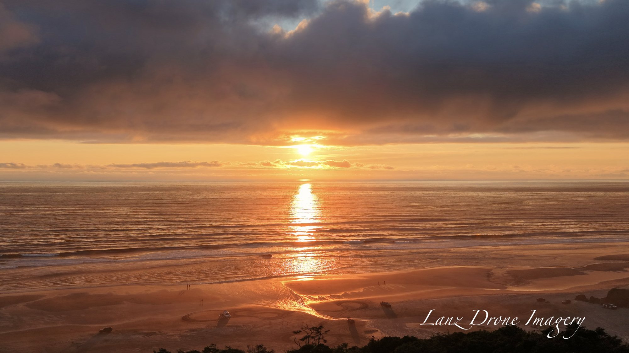 Aerial view of a sunset over the ocean at Pacific City, Oregon, with the sun reflecting across the water and onto the beach